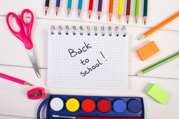 School accessories on white boards, back to school inscription in notepad