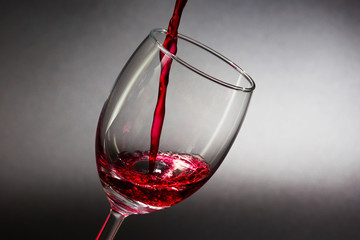 Pouring red wine into the glass against on black background