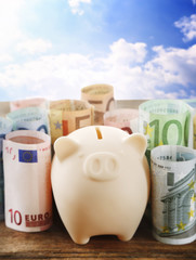 Sticker - Piggy bank with money on blue sky background