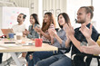 © amenic181 - Group of businesspersons cheering and clapping for a co-worker at the office