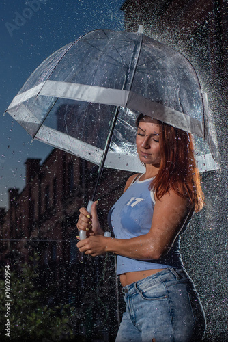 Woman In Blue Jeans In The Rain With Transparent Umbrella At