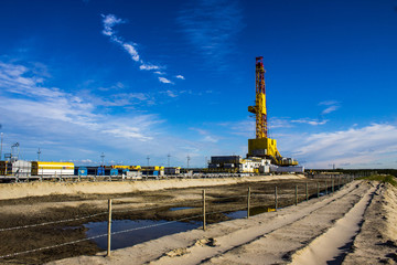 Wall Mural - drilling rig on land with amber behind barbed wire