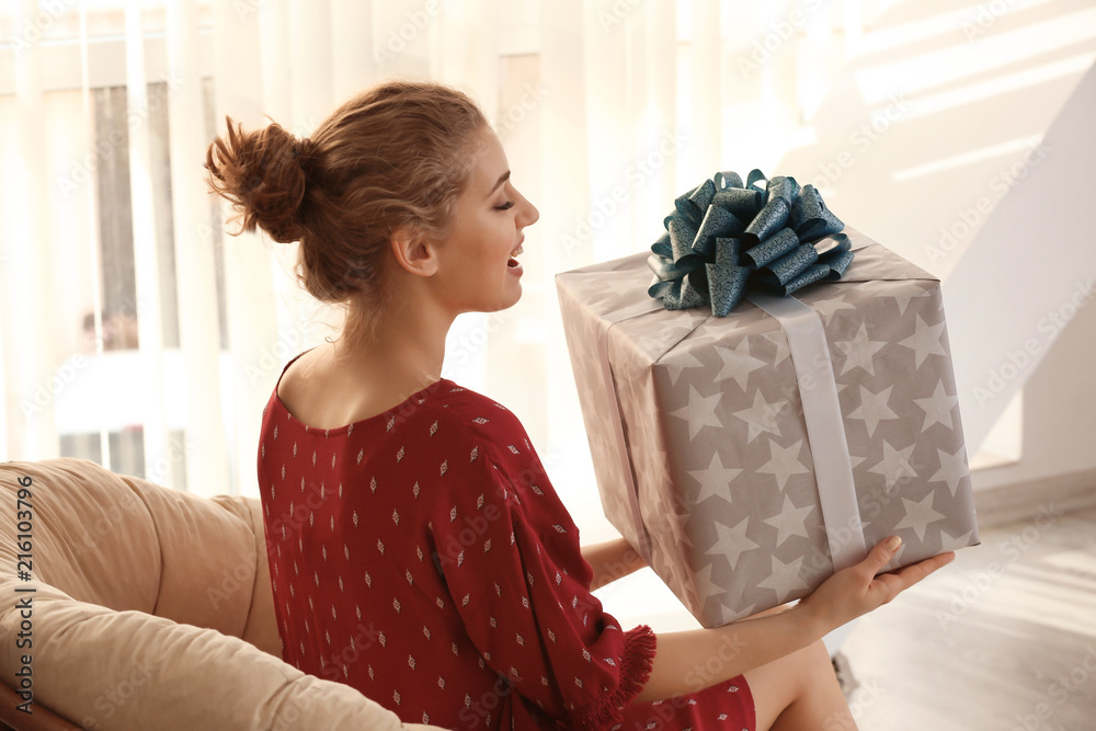 Beautiful young woman with big gift box at home