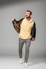 happy young man in stylish autumn jacket posing on grey background