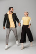 © LIGHTFIELD STUDIOS - fashionable couple of models holding hands and looking at each other on grey background