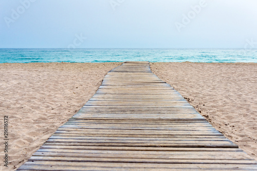 Fotografía Wooden boardwalk at beach in sand and sea in the background