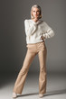© LIGHTFIELD STUDIOS - elegant fashionable woman posing in white sweater and beige pants, on grey