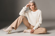 © LIGHTFIELD STUDIOS - attractive fashionable woman posing in white trendy sweater, beige pants and autumn heels, on grey