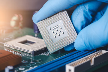 The technician is laying a CPU on the socket of the computer motherboard. the concept of computer, service, electronics, hardware, repairing, upgrade and technology.