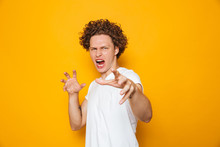 Photo Of Aggressive Man 20s In Casual T-shirt Screaming And Gesturing At Camera, Isolated Over Yellow Background