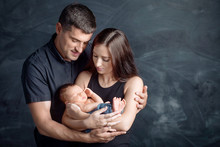 Woman And Man Holding A Newborn. Mom, Dad And Baby. Close-up. Portrait Of  Smiling Family With Newborn On The Hands. Happy Family On A Background.