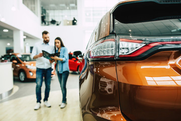 Wall Mural - Young couple buying a new car in dealership