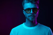 © monchak - Neon light studio portrait of serious man model with mustaches and beard in sunglasses and white t-shirt