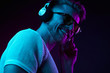 © monchak - Neon light portrait of bearded smiling man in headphones, sunglasses, white t-shirt. Listening to music