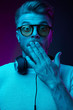 © monchak - Neon light portrait of surprised man with headphones on neck, in sunglasses and white t-shirt.