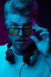 © monchak - Neon light portrait of astonished man with headphones on neck, in sunglasses and white t-shirt.