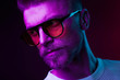 © monchak - Neon light close-up portrait of serious man with mustaches and beard in orange sunglasses and white t-shirt