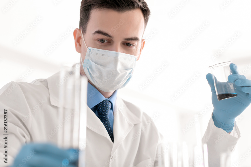 Scientist holding glass beaker with sample in laboratory