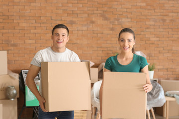 Young couple with boxes indoors. Moving into new house