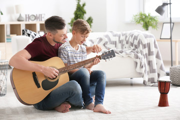 Wall Mural - Father teaching his son to play guitar at home