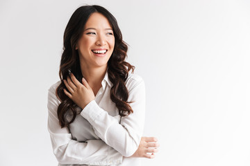 Sticker - Image of charming chinese woman with long dark hair looking aside at copyspace and laughing, isolated over white background in studio