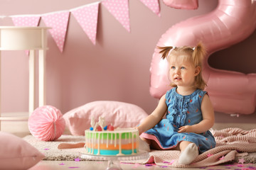 Wall Mural - Cute little girl with delicious cake sitting on carpet in room decorated for birthday party