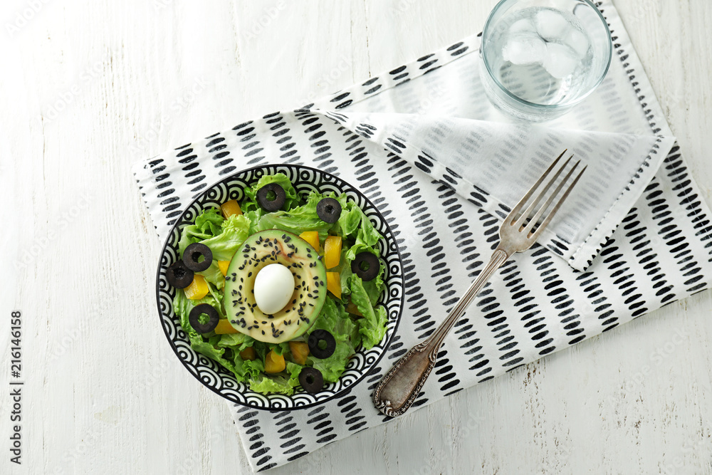 Bowl with tasty avocado salad on table