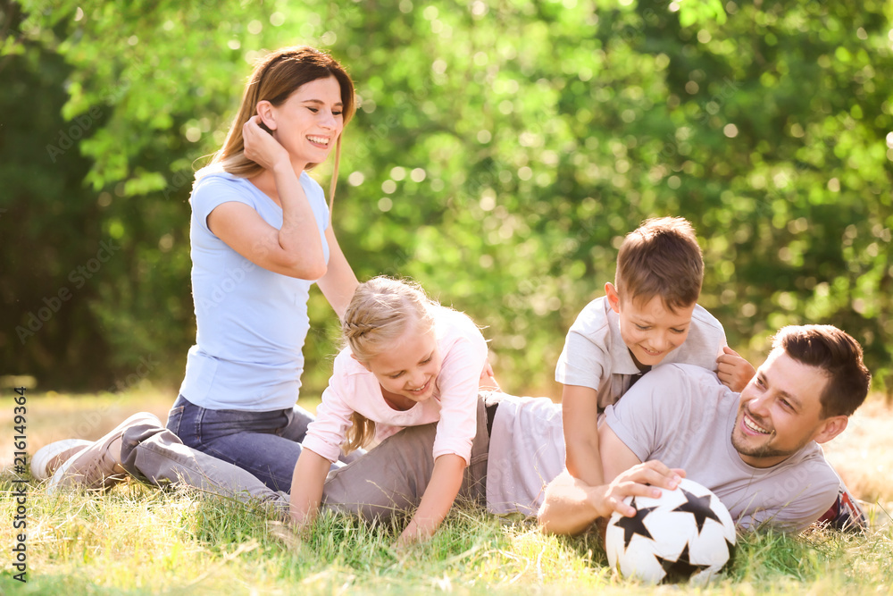 Happy family playing with ball outdoors
