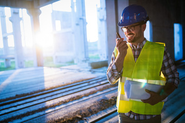 Male architect communicating on walkie-talkie at site