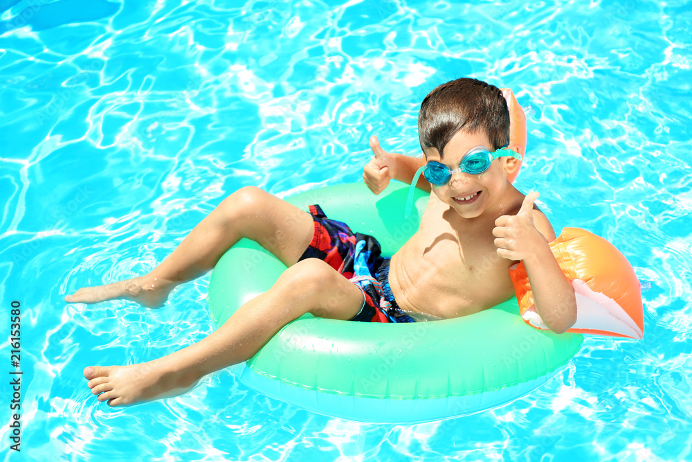 Cute little boy with inflatable ring resting in swimming pool