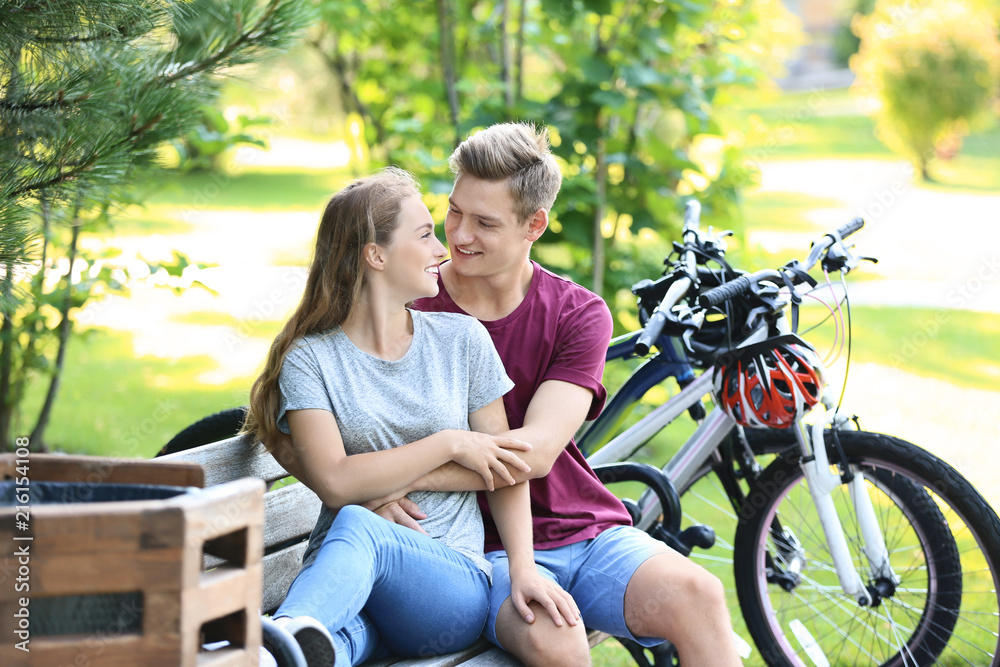 Young couple resting after riding bicycles in park