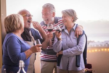 cheerful and smiling group of adult people njoy the cocktail leisure activity outdoor at the terrace. summer season and laugh. beautiful retired people in funny lifestyle together in friendship..