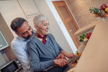 Wall Mural - Happy mature couple making dinner together at home