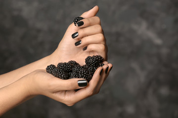 Hands of beautiful young woman with professional manicure holding blackberry on dark grey background