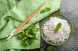 Bowl with boiled white rice and fresh mint on grey textured background