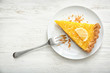 Plate with piece of tasty lemon pie on white wooden table