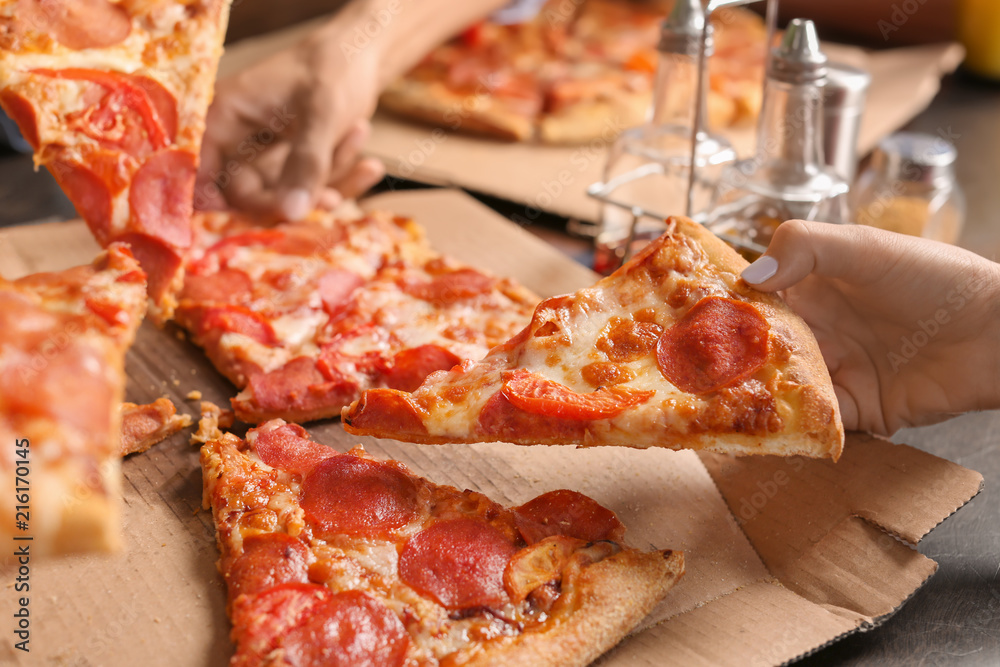 Young people eating delicious pizza indoors