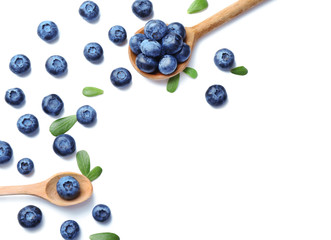 Wooden spoons with ripe blueberries on white background