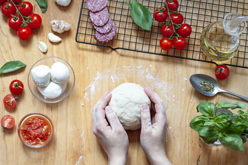 Pizza preparation on the wooden table. Food top view. Woman is making dough flat lay