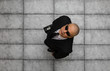 © serikbaib - businessman in black suit, top view, on gray concrete floor background.