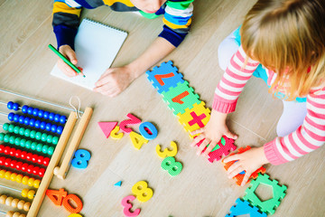 Wall Mural - little boy and girl learn to write and calculate numbers
