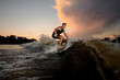 © fesenko - Handsome young man wakesurfing down the river waves