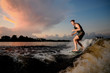 © fesenko - Muscular man riding on wakesurf down the river during sunset