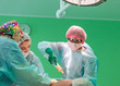 © Georgii - cosmetic liposuction surgery in actual operating room, group of surgeons working with cannula