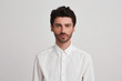 © timtimphoto - isolated shot of young handsome man with beard, wears casual white shirt, has serious expression, standing over white studio background. Headshot of stylish  male