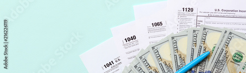 Cuadros en Lienzo Tax forms lies near hundred dollar bills and blue pen on a light blue background