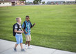 © Brocreative - Two diverse school kids walking home together after school and talking together. Back to school photo of  diverse school children wearing backpacks in the school yard