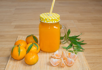 Still life. A transparent mug with a handle with freshly squeezed tangerine juice. And fresh tangerines. 