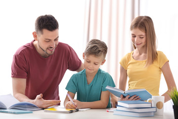 Wall Mural - Brother and sister doing homework with father