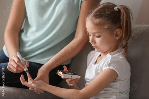Cuadros en Lienzo Woman and her diabetic daughter with lancet pen and digital glucometer taking bl